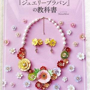 Puede incluir: Un libro titulado "Joyería de Resina" con una portada rosa y un collar de joyería de resina colorido en la portada. El libro es de Nana Akua y está publicado por Pomadour's Craft Cafe.