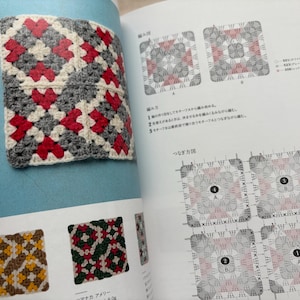 Puede incluir: Un cuadrado de ganchillo con un patr&oacute;n geom&eacute;trico rojo, gris y blanco se muestra en un libro abierto. La p&aacute;gina tambi&eacute;n muestra diagramas y ejemplos de otros patrones de ganchillo. El cuadrado es un primer plano, mostrando la textura y los colores.
