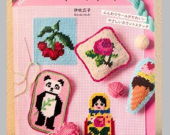 May include: A craft book titled "はじめてのニードルポイント" by Hiroko Ibuki featuring needlepoint projects on a pink grid background. Visible designs include cherries, a rose, a panda, a matryoshka doll, an ice cream cone, and a heart.