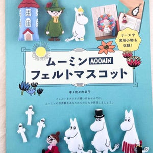 May include: A book cover with a blue background and the title "Moomin Felt Mascot" in Japanese. The cover features illustrations of Moomin characters, including Moomin, Sniff, and Little My, made from felt. The book is part of the "Lady Boutique" series.