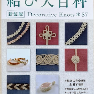 Puede incluir: Un libro de manualidades titulado 結び大百科 Decorative Knots 87 que presenta una cuadrícula de ocho fotografías que muestran diversas técnicas de nudos, patrones trenzados y diseños de macramé sobre fondos de tela de color sólido.