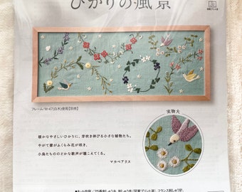 May include: A cross-stitch embroidery kit featuring a light blue background with a bird, flowers, and leaves. The kit includes 25 count Aida cloth, embroidery floss, a needle, and instructions. The finished piece measures approximately 18.5 inches by 43 inches.