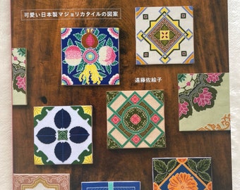 Op de afbeelding: Boekomslag met de titel "Cross-Stitch x Antique Tile Design" in het Japans. De omslag toont kleurrijke kruissteekontwerpen van antieke Japanse tegels.
