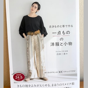 May include: A book cover featuring a person wearing a black long-sleeved top, a patterned obi belt, and wide-leg trousers with a light-coloured floral print. The text includes Japanese characters, the title, and a red circle with 24.5 text.