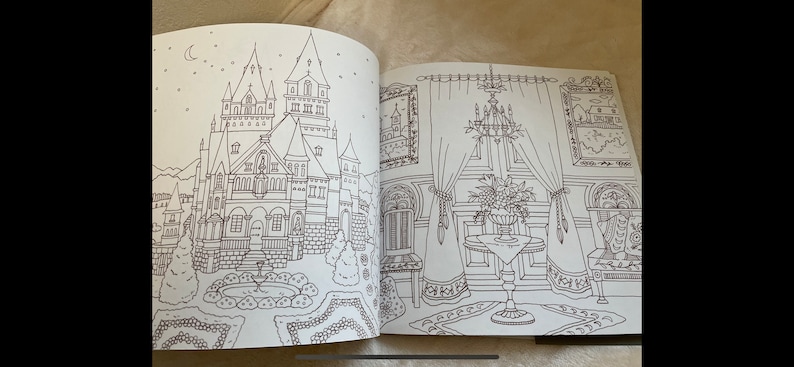 Puede incluir: P&aacute;ginas de un libro para colorear abierto con dibujos lineales detallados de un castillo con una fuente y una habitaci&oacute;n con una l&aacute;mpara de ara&ntilde;a, una mesa y cortinas. Las ilustraciones son en blanco y negro, listas para colorear.