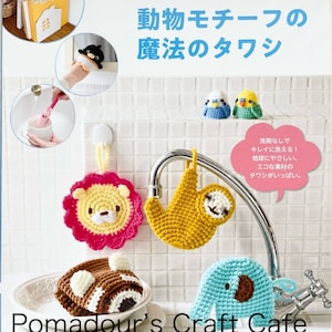 May include: A book cover featuring various crocheted animal-shaped scrubbers, including a lion, sloth, and elephant. The cover has Japanese text and the words "Pomadour's Craft Cafe". The scrubbers are in various colors, including yellow, pink, and blue.