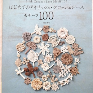 May include: A book titled "Irish Crochet Lace Motif 100" with Japanese text. The cover displays a collection of crocheted lace motifs in various shapes and neutral colours, including flowers and leaves. The book is on a blue background.