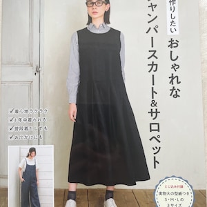 May include: A book cover featuring a woman wearing a black pinafore dress and white shoes. The book title is "Handmade Stylish Jumper & Overall Dress" in Japanese. The cover also includes a smaller image of a woman wearing a blue denim pinafore dress.