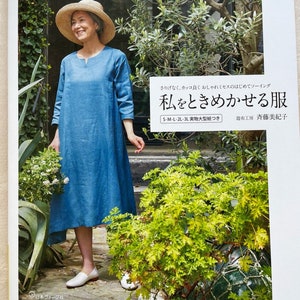 Puede incluir: Una portada de libro con una mujer que lleva un vestido azul claro y un sombrero de paja. El título del libro es "私をときめかせる服", que se traduce como "Ropa que me hace feliz". El libro forma parte de la "Head Warming Life Series" y está publicado por "日本ヴォーグ社", que se traduce como "Japan Vogue Co., Ltd.".