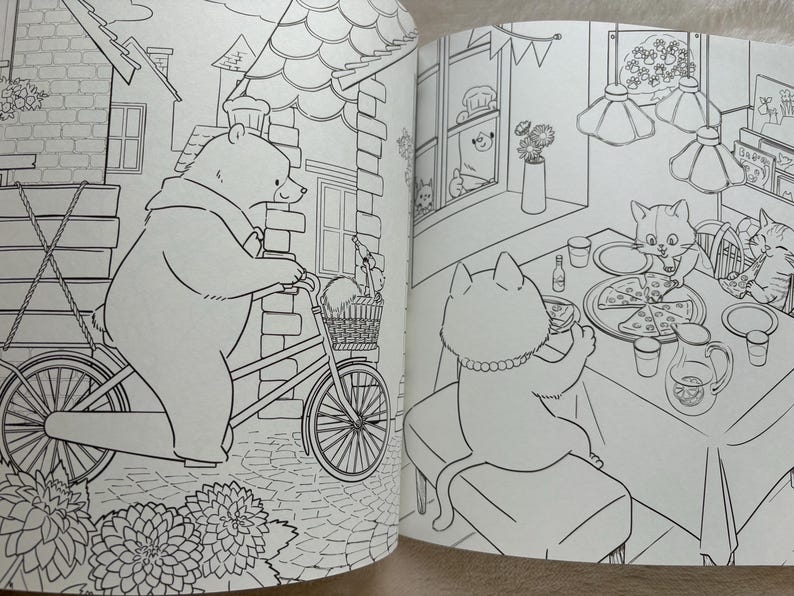May include: Black and white illustration from a children's coloring book. A bear rides a bicycle with a basket, while cats enjoy pizza at a table. The scene is set in a town with buildings and flowers.