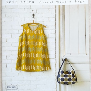 May include: A book titled "斉藤謠子の毎日着る服、毎日持つ布バッグ Yoko Saito Casual Wear & Bags" with a yellow and white patterned dress and a polka dot bag hanging on a white brick wall. The book includes a pattern for the dress and bag.