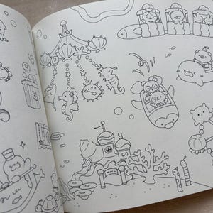 May include: A double-page spread from a colouring book, depicting various cartoon sea creatures and scenes. The illustrations include a carousel with seahorses and pufferfish, and characters in vehicles. All drawings are outlined in black.