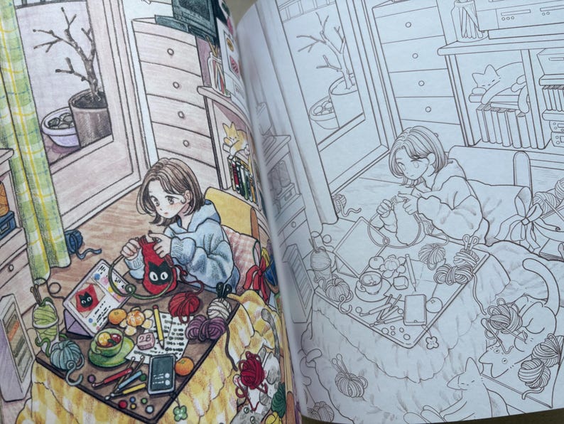 May include: A colouring book page featuring a detailed illustration of a person knitting at a table. The scene includes yarn balls, a tablet displaying a cat graphic, a cup, pencils, and a cat resting nearby, shown in both coloured and line art versions.
