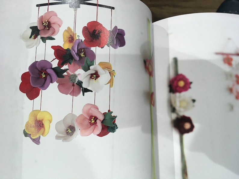 May include: A colorful felt flower mobile with red, pink, white, yellow, and purple flowers hanging from a black metal frame.