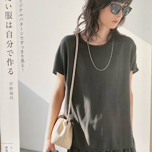 Può includere: Una maglietta nera con una collana a catena argentata e una borsa bianca. Il testo "UNO" e "Modello originale, facile da vedere!" è visibile sullo sfondo. Il testo "Fai i tuoi vestiti" è anche visibile sullo sfondo.