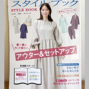 Op de afbeelding: Een tijdschriftomslag met een vrouw in een lichtgrijze jurk. De titel is in het Japans, met extra Japanse en Engelse tekst. De omslag toont kledingontwerpen en de tekst "Pomadour's Craft Cafe".
