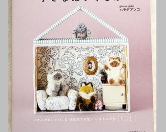 May include: A light pink craft book titled "パンチニードルでつくる 小さなぬいぐるみ" featuring a house-shaped diorama on the cover. The diorama contains miniature fuzzy animal figures, a small chair, a cabinet, and a framed picture against a floral wallpaper background.
