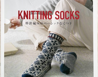 May include: A book titled "KNITTING SOCKS" with Japanese text, showing a person wearing patterned socks. The socks are navy blue and white, with a geometric design. The book cover has the "applemints" logo.