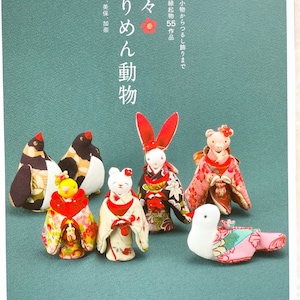 Pode incluir: Uma capa de livro com o título "Fukufuku Chirimen Doubutsu" em japonês. A capa apresenta uma ilustração colorida de vários animais pequenos de tecido vestidos com roupas japonesas tradicionais.