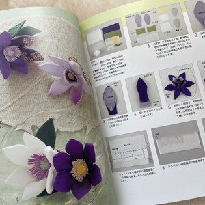 May include: A book with instructions on how to make a purple flower from fabric. The book has a Japanese title, "鉄線袋", and includes diagrams and photos of the process.