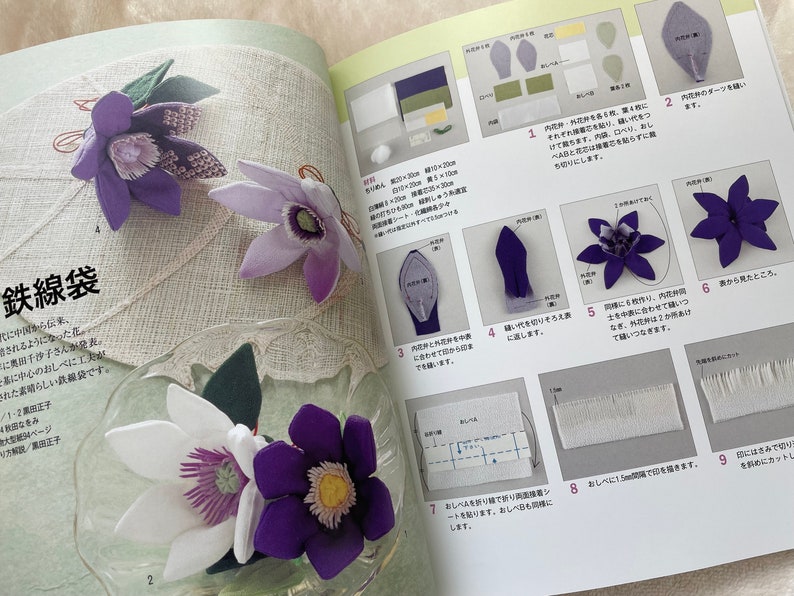 May include: A book with instructions on how to make a purple flower from fabric. The book has a Japanese title, "鉄線袋", and includes diagrams and photos of the process.