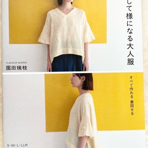 Può includere: Una copertina di libro con una donna che indossa una blusa di lino bianca con scollo a V. Il titolo del libro è "Abiti per adulti facili da realizzare ed eleganti" e il testo "Tutto può essere fatto, può essere indossato a rotazione" è sul lato destro della copertina. Il libro fa parte della "Heart Warming Life Series" ed è di Flavour Works.