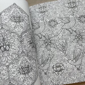 May include: Open book pages featuring intricate black and white floral and bird illustrations. The detailed drawings include stylized flowers, leaves, and birds, creating a pattern suitable for coloring or artistic projects. The design is reminiscent of vintage botanical art.