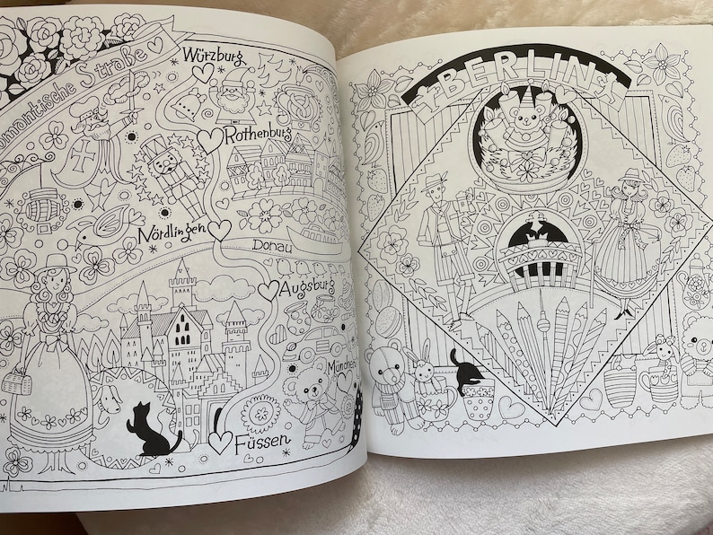 May include: A black and white coloring book page with illustrations of German cities and landmarks. The page includes the text "Romantische Stra&szlig;e", "W&uuml;rzburg", "Rothenburg", "N&ouml;rdlingen", "Donau", "Augsburg", "F&uuml;ssen", and "BERLIN".