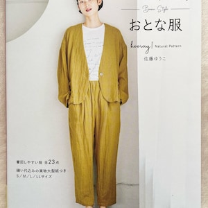 May include: A book cover featuring a woman wearing a yellow linen jacket and pants. The title of the book is "Basic Style: Otona-fuku" and the subtitle is "hooray! Natural Pattern" by Satou Yuko. The book is part of the Heart Warming Life Series by Japan Vogue.