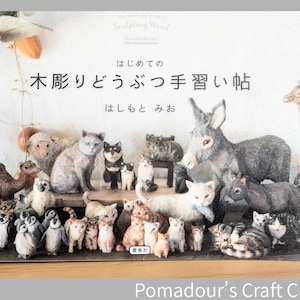Könnte beinhalten: Eine Sammlung handgeschnitzter Holztiere, darunter Katzen, Pinguine, ein Esel und eine Giraffe, auf einem Regal. Die Figuren sind in realistischen Farben und Texturen bemalt. Japanischer Text ist ebenfalls vorhanden.