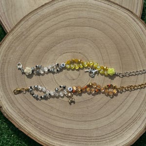 May include: Two beaded bracelets with charms. The top bracelet spells "WHITE HORSE" in yellow beads with silver accents. The bottom bracelet spells "BOBBY" in white beads with silver accents. Both bracelets have a silver clasp.
