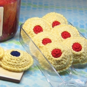 Puede incluir: Primer plano de galletas de crochet en un recipiente de plástico transparente. Las galletas son amarillas y tienen centros rojos. Las galletas están dispuestas en círculo.