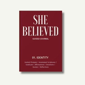 May include: A burgundy-coloured guided journal with the words "SHE BELIEVED" in white, bold font. Below, it reads "GUIDED JOURNAL." The journal's cover also includes "01. IDENTITY" and a list of prompts, scriptures, affirmations, devotions, quotes, and reflections.