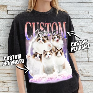 Puede incluir: Camiseta negra con un gráfico de cinco gatos blancos y marrones sobre una nube con un brillo rosa y morado. El texto "CUSTOM Your pet" está por encima de los gatos y "CUSTOM PET NAME" está a la derecha de los gatos.