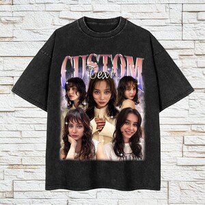 Pu&ograve; includere: T-shirt nero con un aspetto vintage sbiadito. La parte anteriore presenta un collage fotografico di una donna con la scritta "CUSTOM Text" in un font retr&ograve;. La maglietta ha un girocollo e maniche corte.