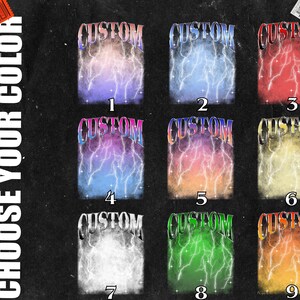 May include: Nine different colour variations of a graphic tee design featuring the word "CUSTOM" in a bold, metallic font with lightning bolts behind it. The colours include pink, blue, red, purple, orange, yellow, white, green, and orange.
