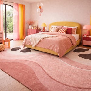May include: A bedroom with a yellow bed frame, pink bedding, and a patterned rug. The room features pink and yellow curtains, a pink dresser, and a matching nightstand. A large window and a yellow chair complete the decor.