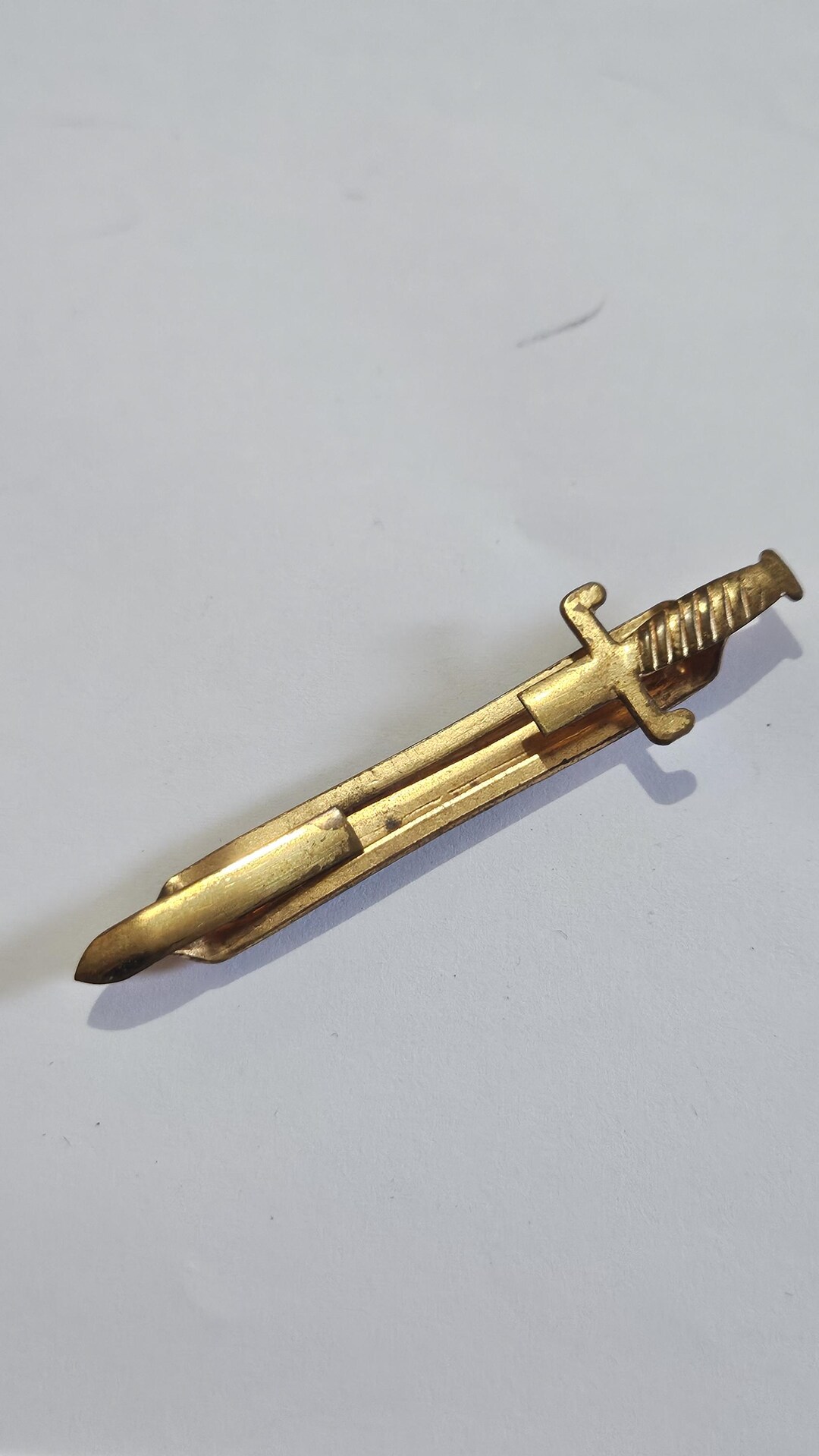 Vintage gold tone and mother of pearl tie pin in a sword design. yenihayathastan