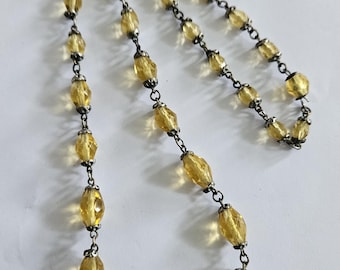 May include: A silver chain necklace with faceted yellow glass beads.