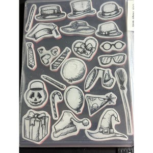 May include: Clear plastic stamp set featuring various designs, including hats, ties, glasses, balloons, and a witch's hat. The stamps are in a clear plastic case, perfect for crafting and scrapbooking projects.