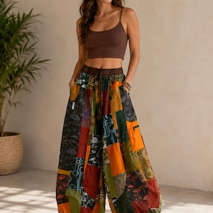 May include: A brown spaghetti strap crop top paired with loose-fitting, wide-leg patchwork trousers. The trousers feature a multi-colored design with orange, green, and dark panels, decorated with a repeating white mushroom and botanical print pattern.