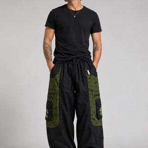 Puede incluir: Una camiseta negra de manga corta combinada con pantalones cargo negros de corte holgado. Los pantalones presentan grandes paneles laterales de color verde oliva decorados con un patr&oacute;n de setas, m&uacute;ltiples bolsillos y cord&oacute;n.
