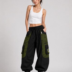 Puede incluir: Una camiseta de tirantes blanca acanalada combinada con pantalones cargo negros con paneles laterales verde oliva. Los pantalones incluyen bolsillos grandes con estampados de hongos, cintura con cord&oacute;n y pu&ntilde;os el&aacute;sticos, con botas negras.