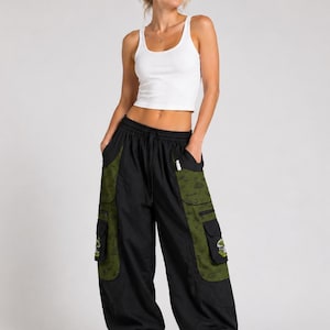 Puede incluir: Una camiseta de tirantes blanca acanalada combinada con pantalones cargo negros con paneles laterales de color verde oliva. Los pantalones incluyen bolsillos grandes con parches de hongos, cintura con cord&oacute;n y pu&ntilde;os el&aacute;sticos.