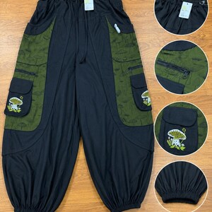 Puede incluir: Pantalones negros con paneles laterales en verde oliva con estampado de setas. Los pantalones incluyen grandes bolsillos cargo con parches bordados de setas, cintura con cord&oacute;n y pu&ntilde;os el&aacute;sticos. Los detalles muestran la cintura, bolsillos con cremallera y pu&ntilde;os.