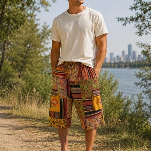May include: A plain off-white short-sleeve crew neck t-shirt paired with knee-length patchwork shorts featuring a drawstring waist, multiple fabric patterns in shades of yellow, orange, and brown, and a visible mushroom graphic on a pocket.