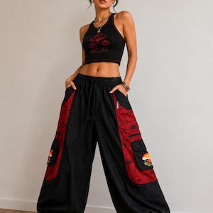 Puede incluir: Un top corto negro de espalda nadadora con un gr&aacute;fico de setas rojas y pantalones cargo negros a juego con paneles laterales rojos, bordados de setas en los bolsillos, cintura con cord&oacute;n y pu&ntilde;os el&aacute;sticos en los tobillos, con botas negras.