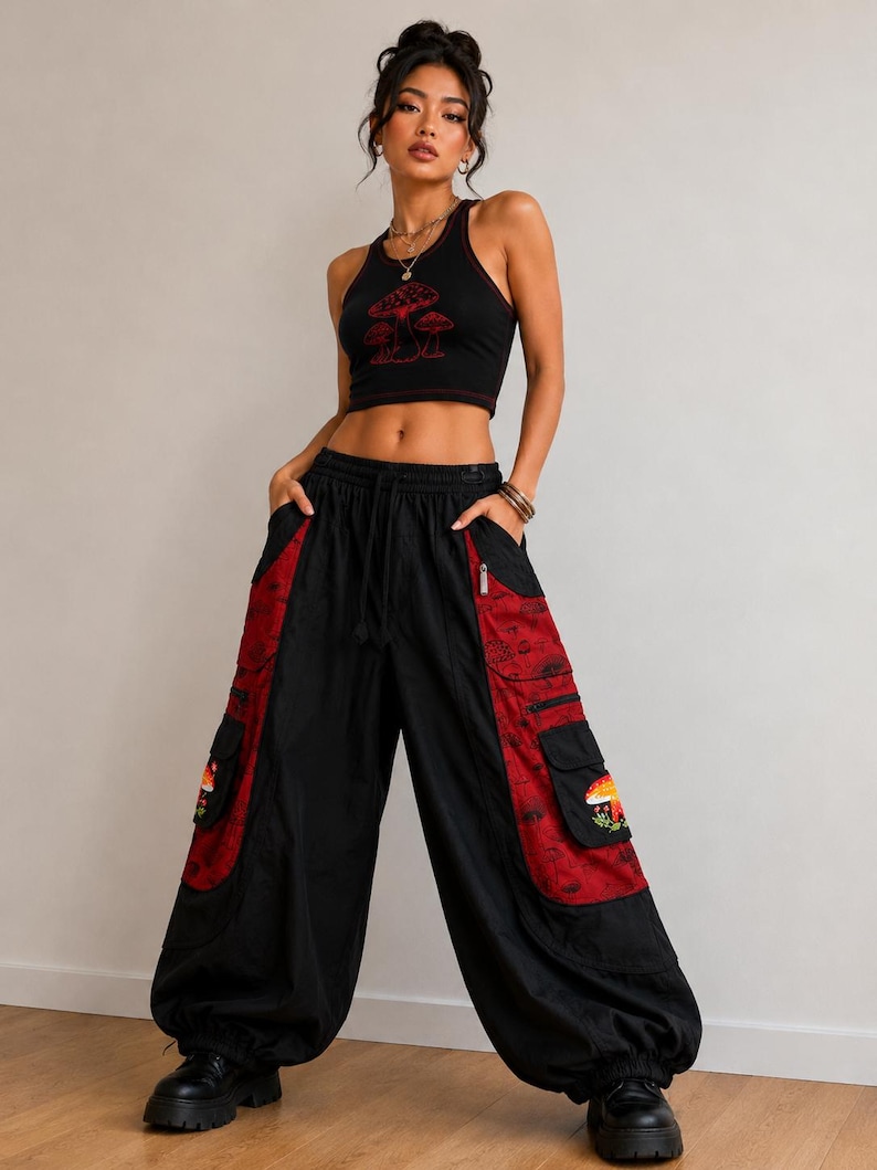 Puede incluir: Un top corto negro de espalda nadadora con un gr&aacute;fico de setas rojas y pantalones cargo negros a juego con paneles laterales rojos, bordados de setas en los bolsillos, cintura con cord&oacute;n y pu&ntilde;os el&aacute;sticos en los tobillos, con botas negras.