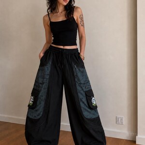 Puede incluir: Una camiseta de tirantes negra combinada con pantalones cargo negros de pierna ancha que presentan grandes bolsillos laterales con paneles de patrones oscuros y bordados de setas en las solapas, con cintura de cord&oacute;n y zapatos de plataforma negros.