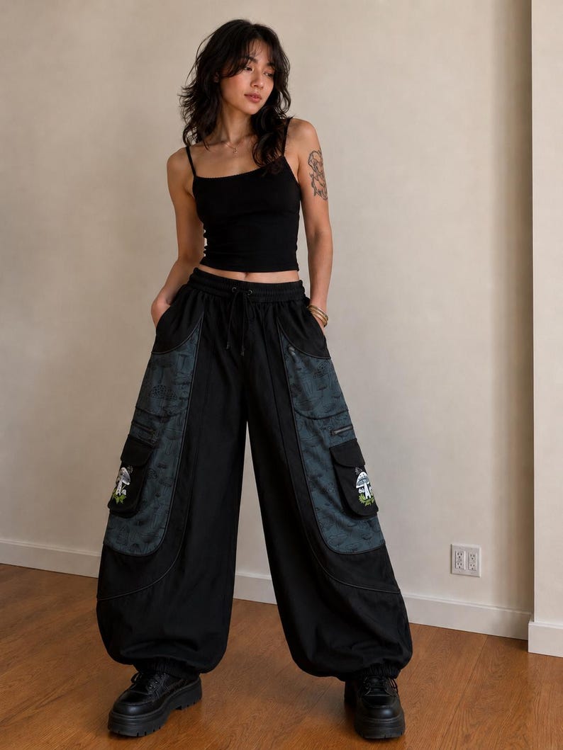 Puede incluir: Una camiseta de tirantes negra combinada con pantalones cargo negros de pierna ancha que presentan grandes bolsillos laterales con paneles de patrones oscuros y bordados de setas en las solapas, con cintura de cord&oacute;n y zapatos de plataforma negros.